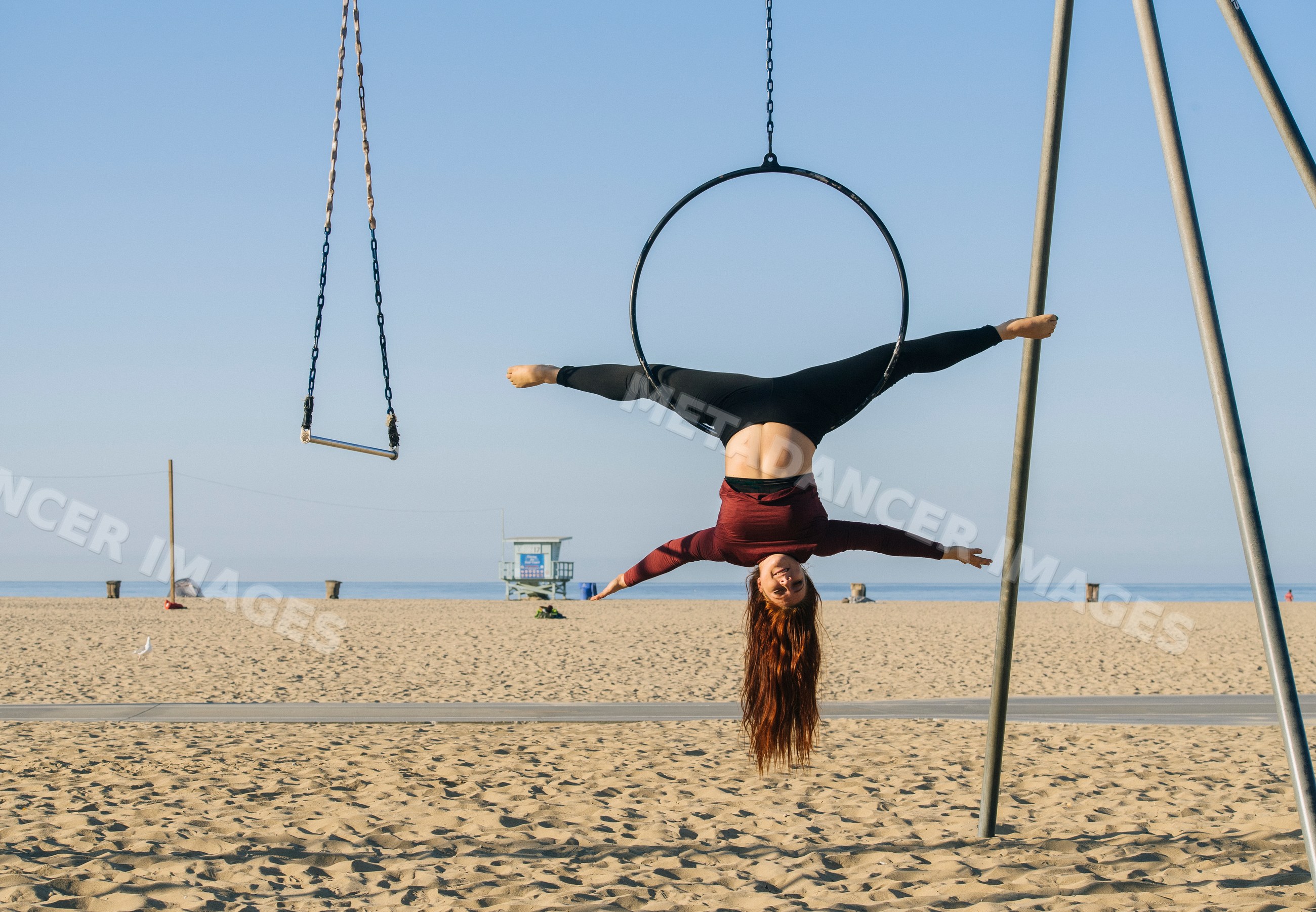 White woman performing split on aerial hoop at California beach