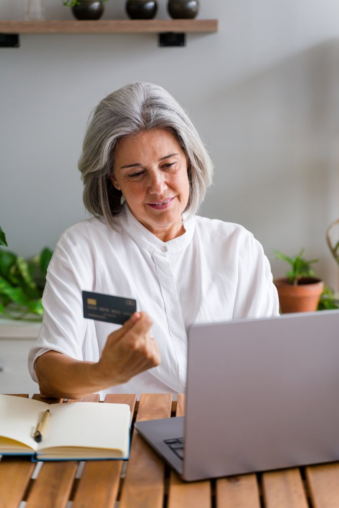 Middle-aged white woman shopping online with credit card and laptop