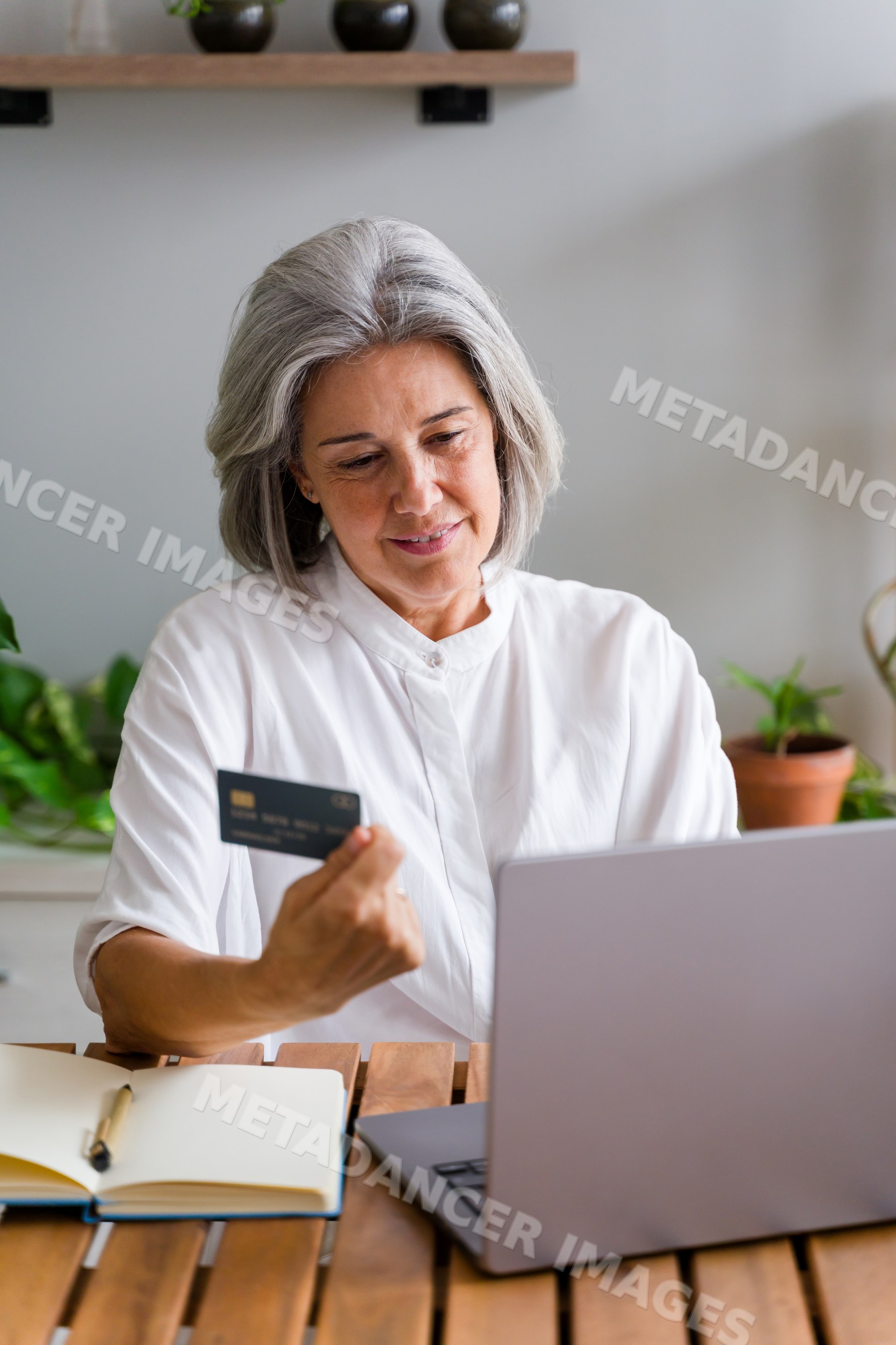 Middle-aged white woman shopping online with credit card and laptop