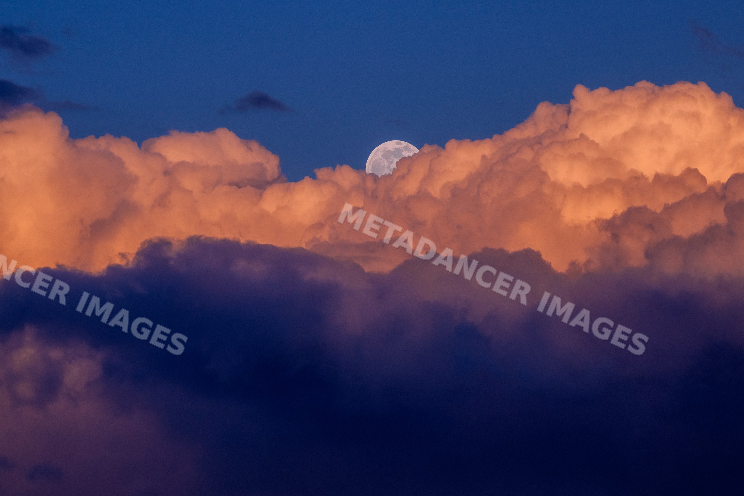 Moon rising over colorful clouds at twilight in Seattle
