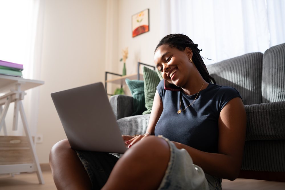 African American woman works on her laptop and talks on the phone