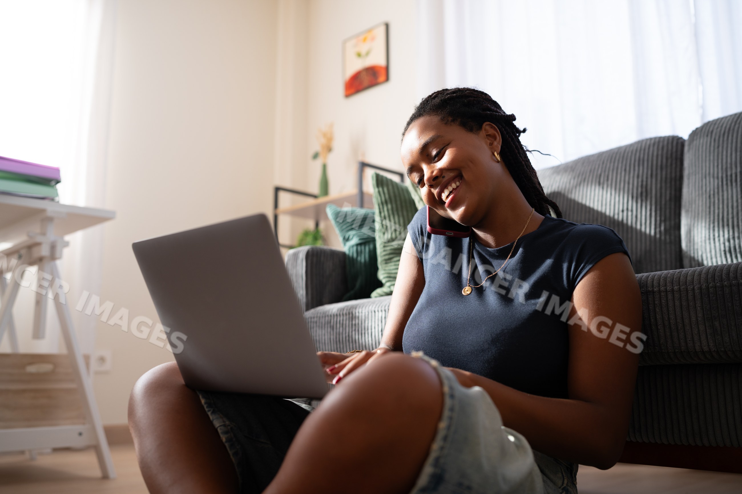 African American woman works on her laptop and talks on the phone