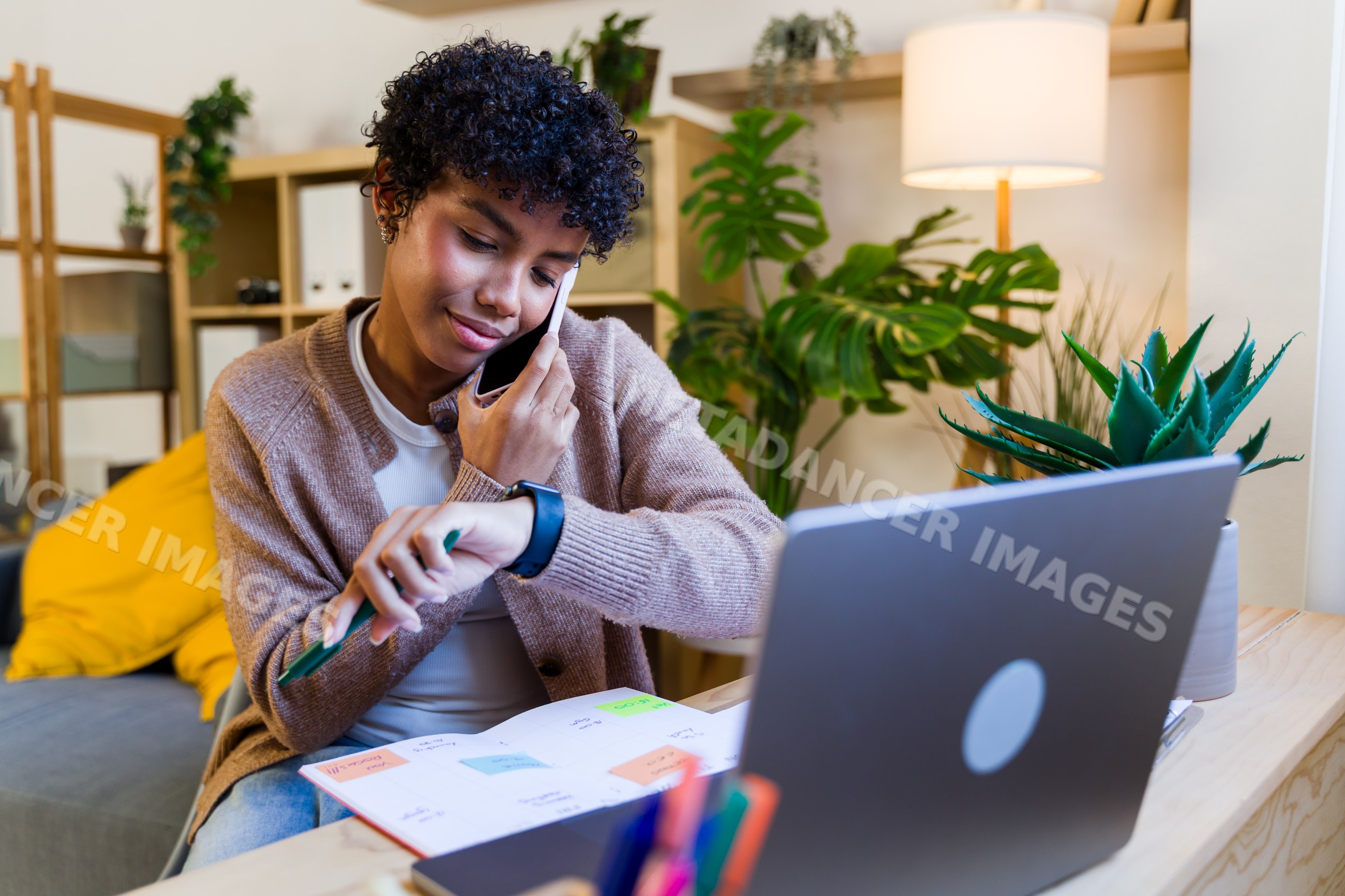 African American woman checking watch while talking on phone