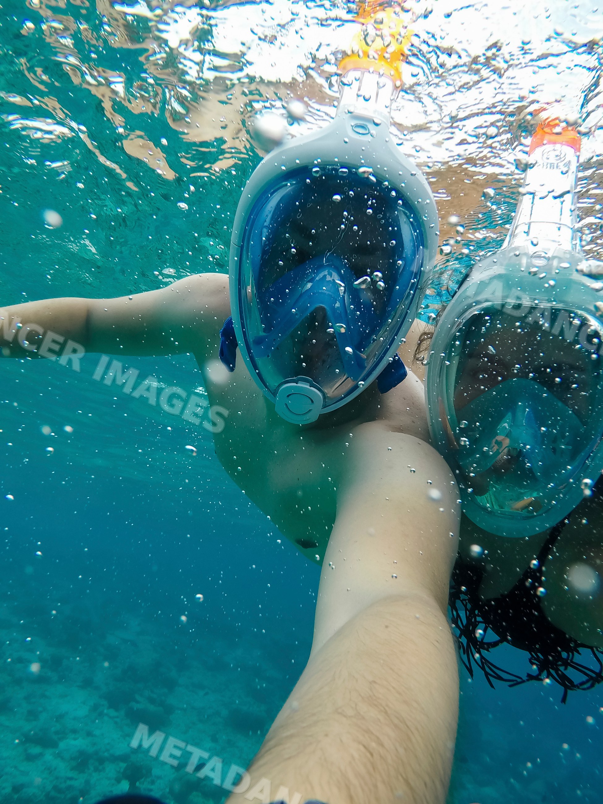 Two people snorkeling underwater with full-face masks