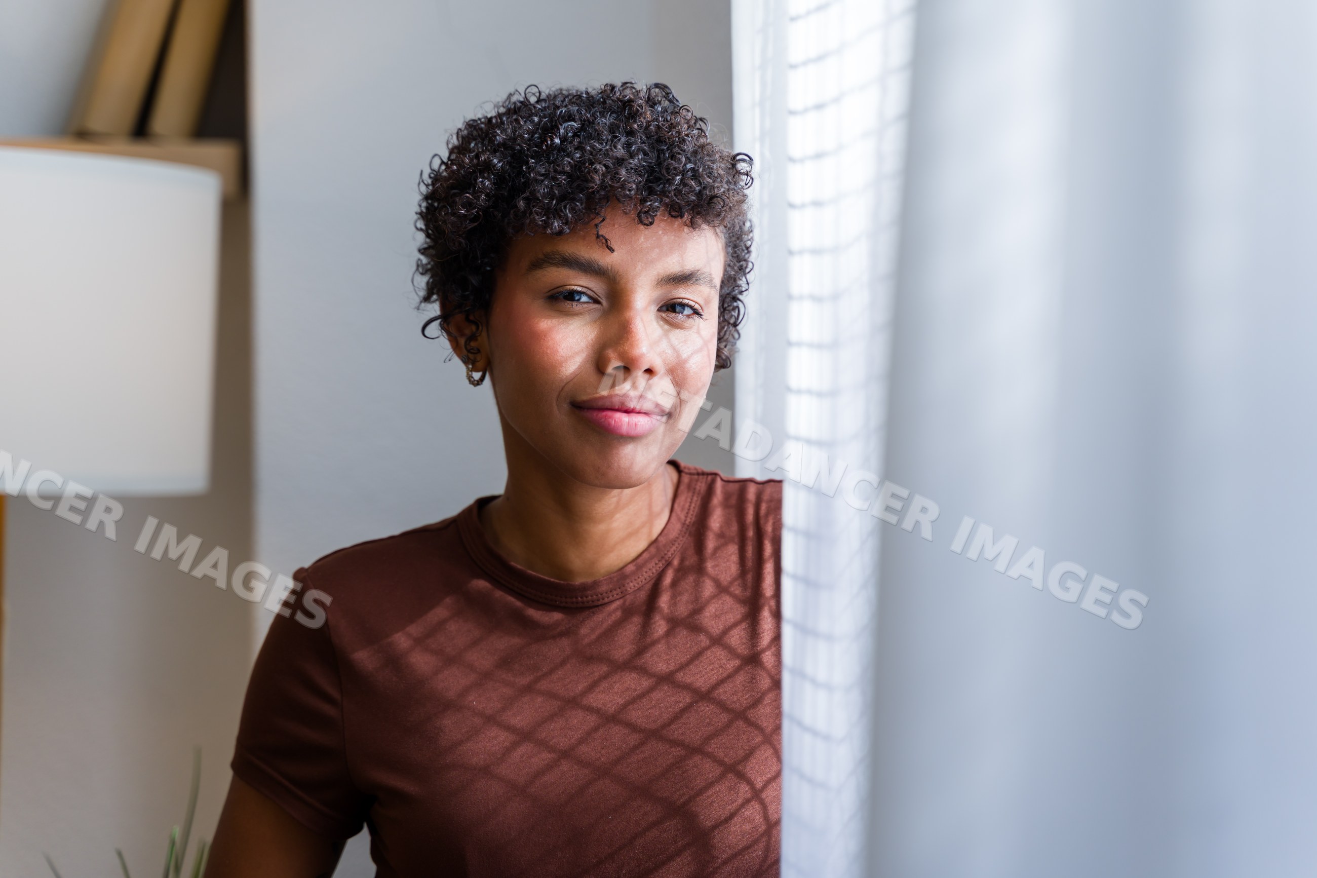 Young African American woman with curly hair looking through window