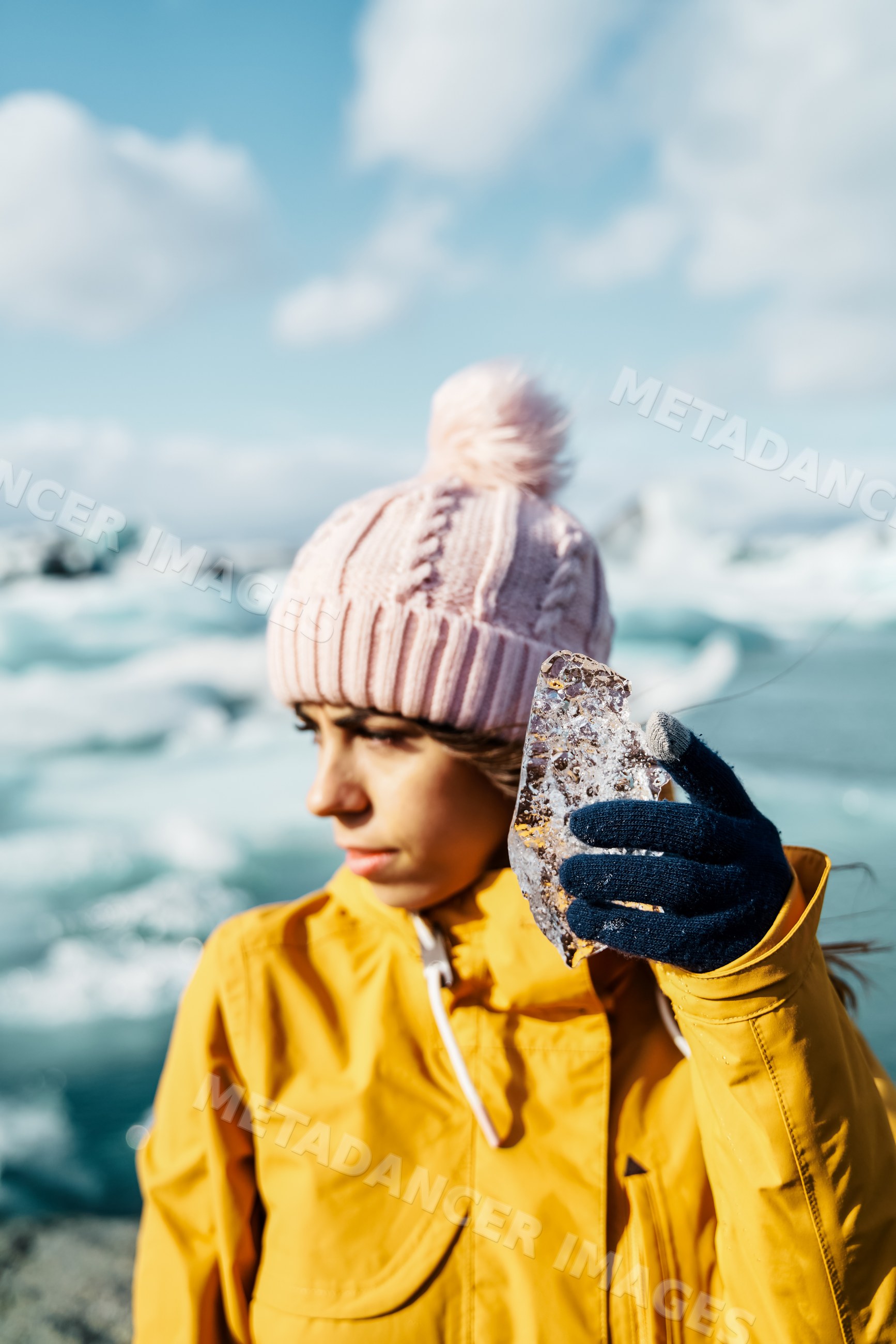 A white woman holds ice near a frozen lake in Iceland during winter