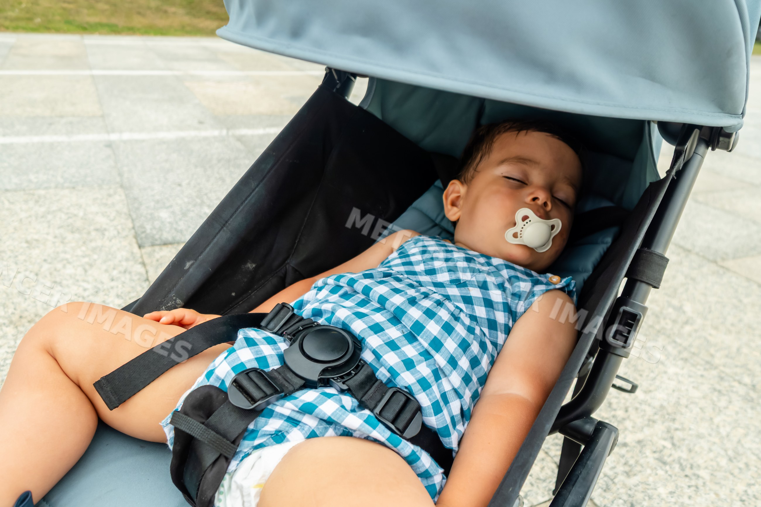 Sleeping baby resting in stroller outdoors with pacifier
