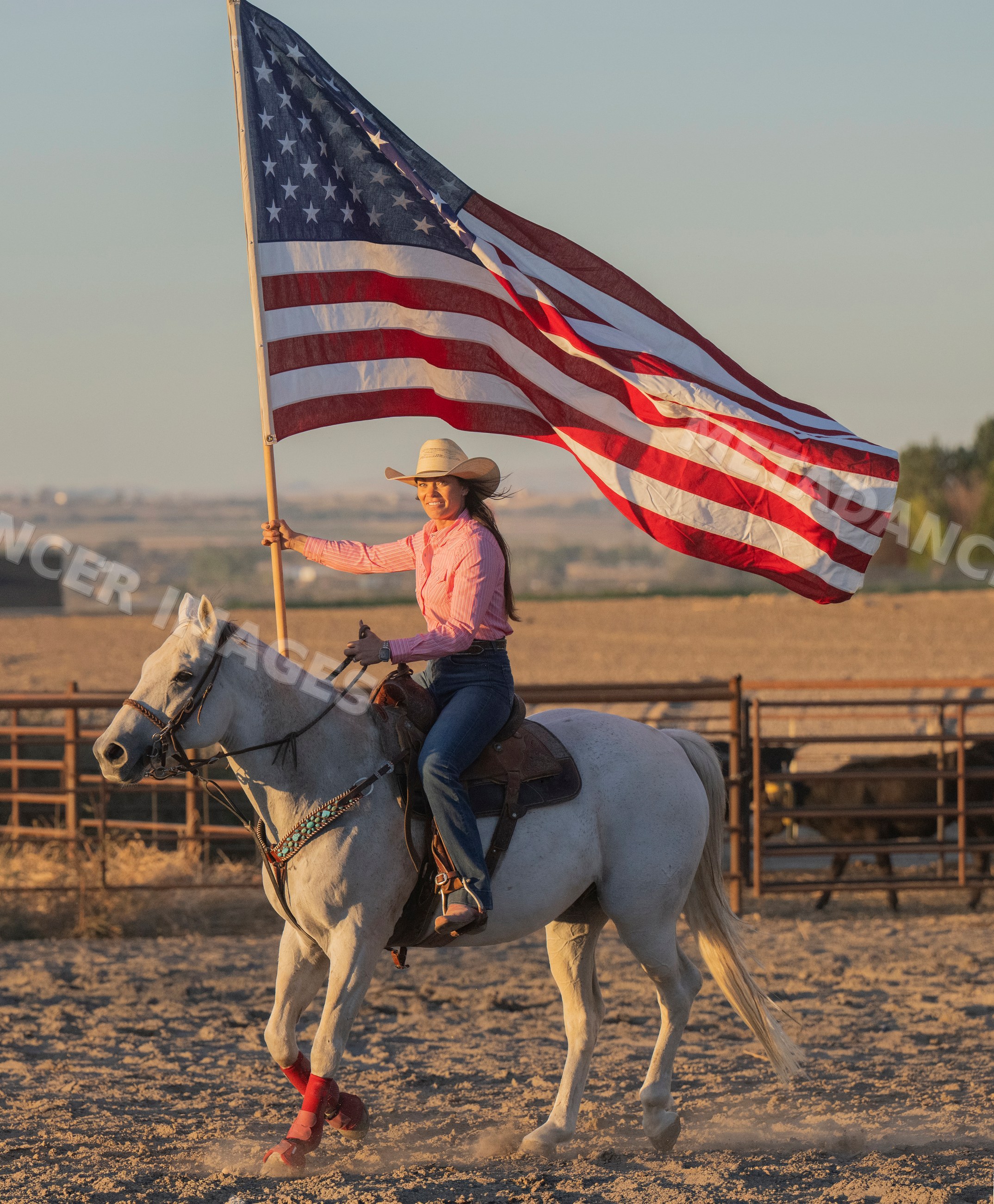 Woman riding white horse holding american flag
