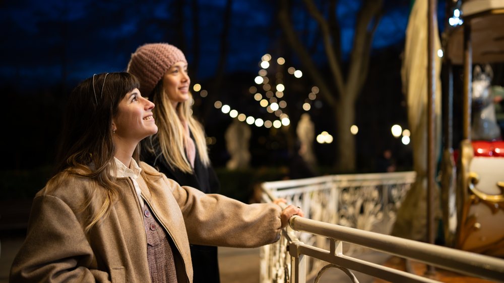 Two white women enjoy festive lights