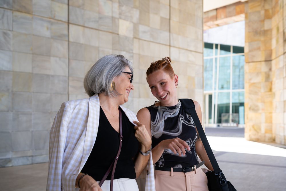 Two businesswomen happily chatting outside modern building