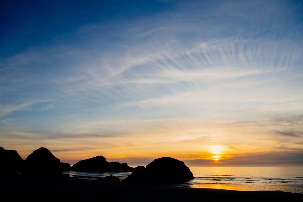 Sunset ocean view with silhouetted rock formations on beach