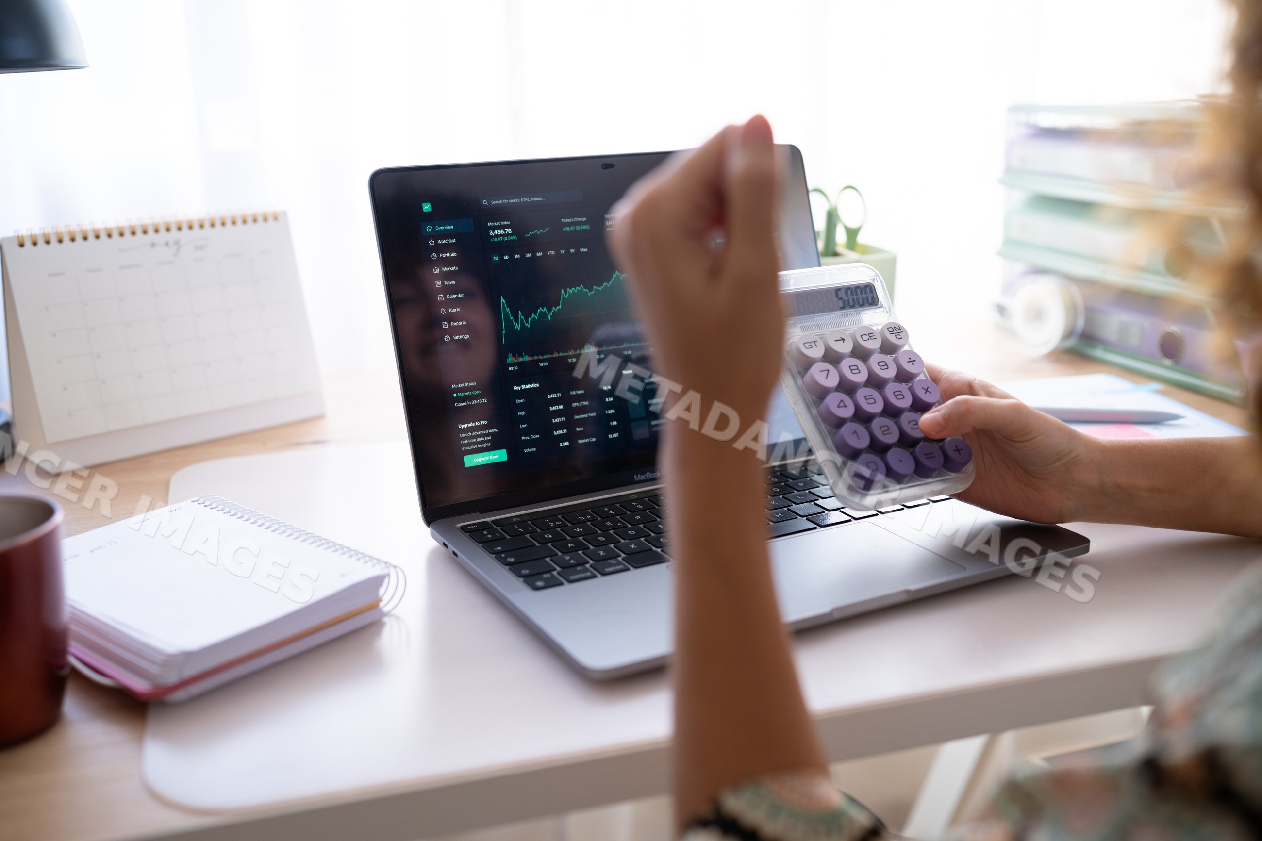 White woman calculating finances with calculator and laptop displaying