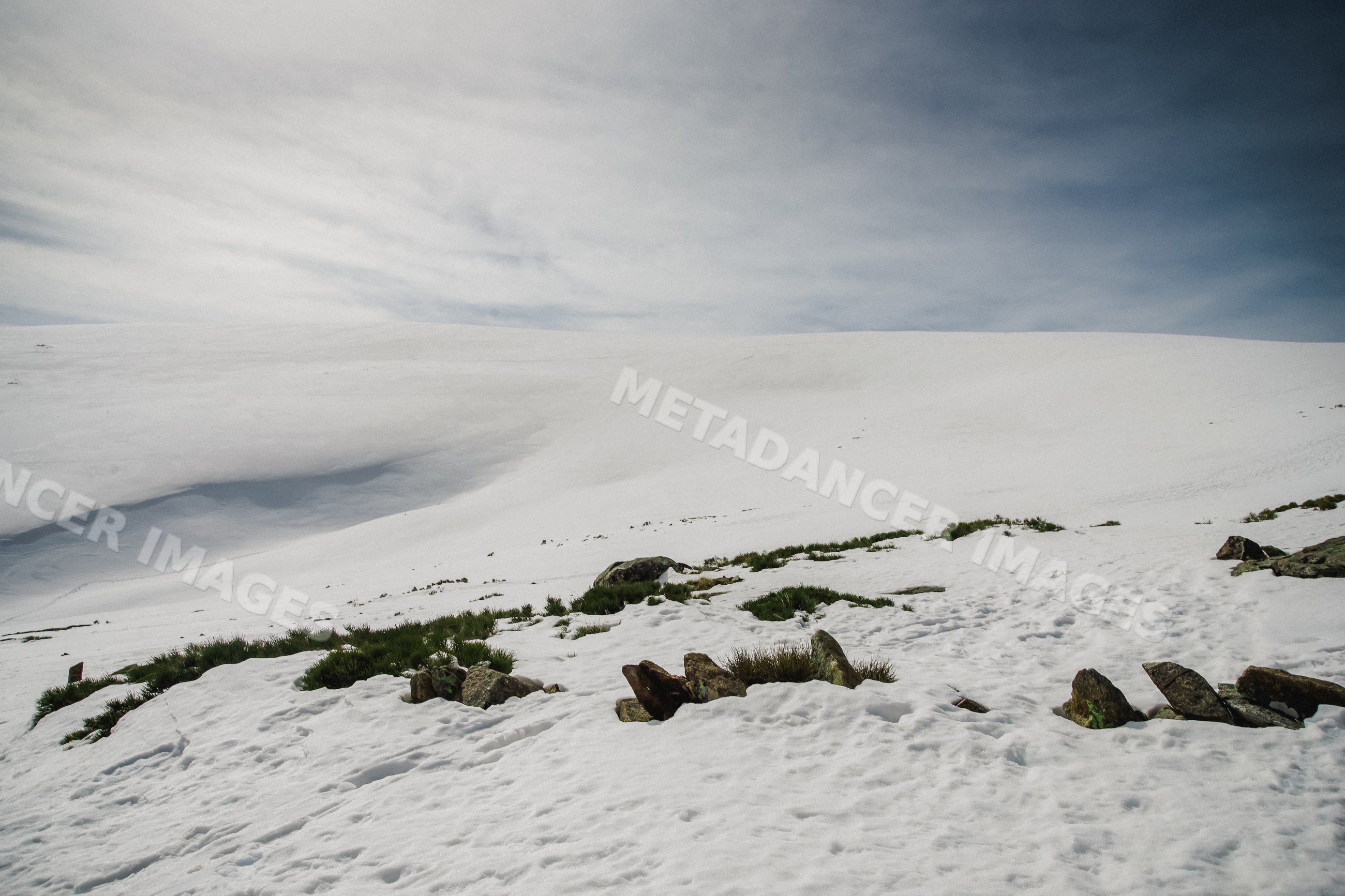 Snow-covered mountain landscape with rocks and grass