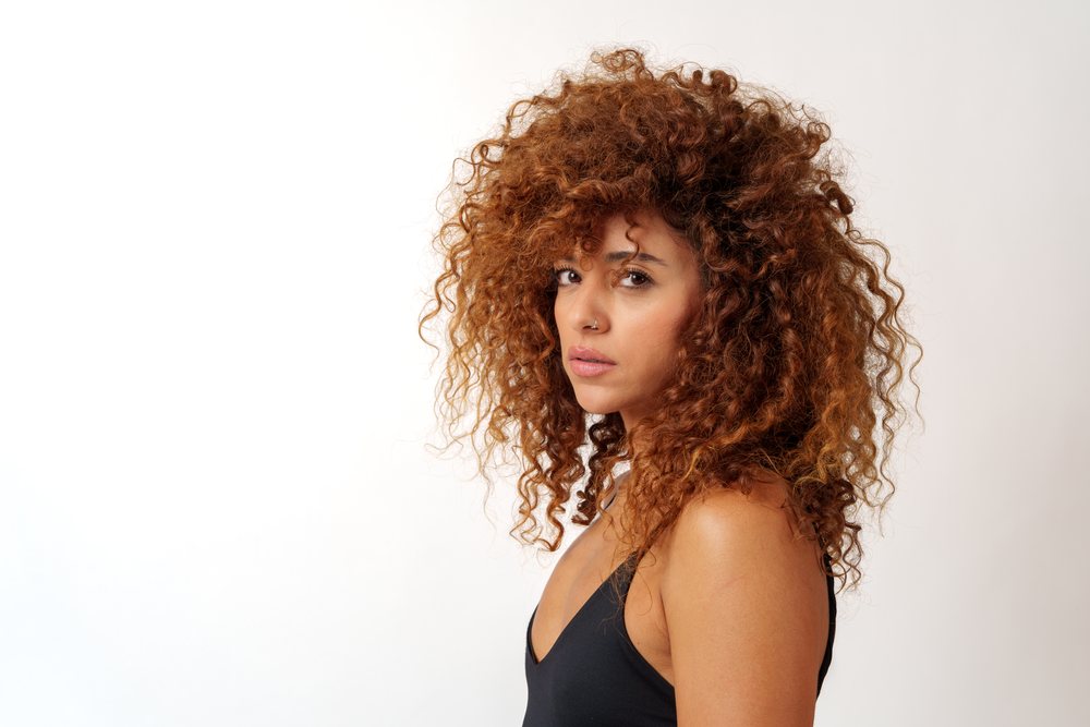 Hispanic woman with voluminous curly red hair and nose ring