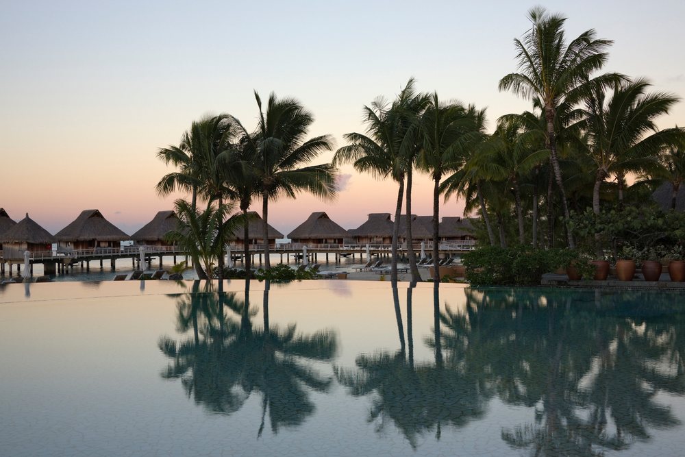 Infinity pool and overwater bungalows at sunset