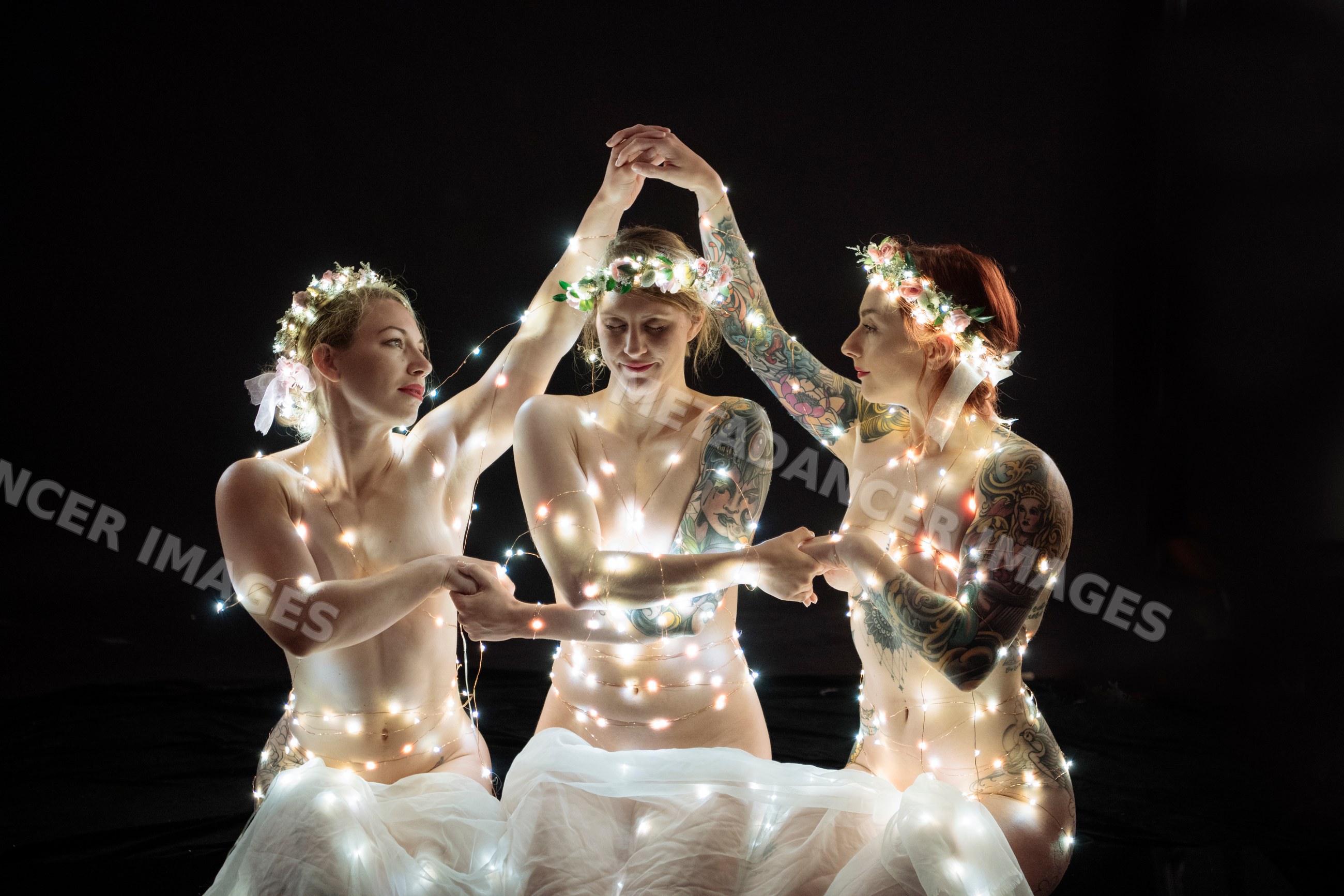 Three tattooed white women wearing flower crowns wrapped