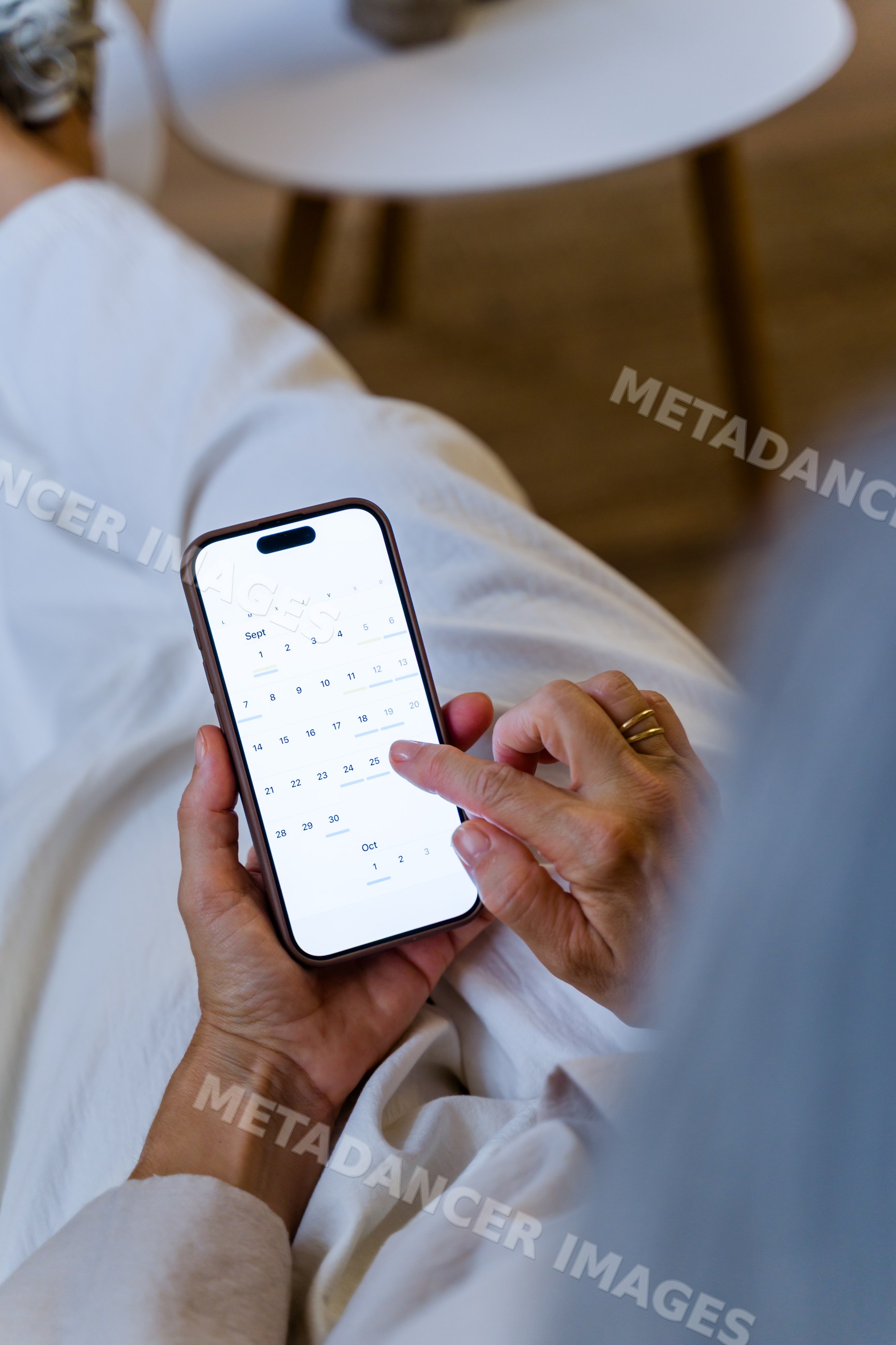White person holding smartphone with calendar app indoors