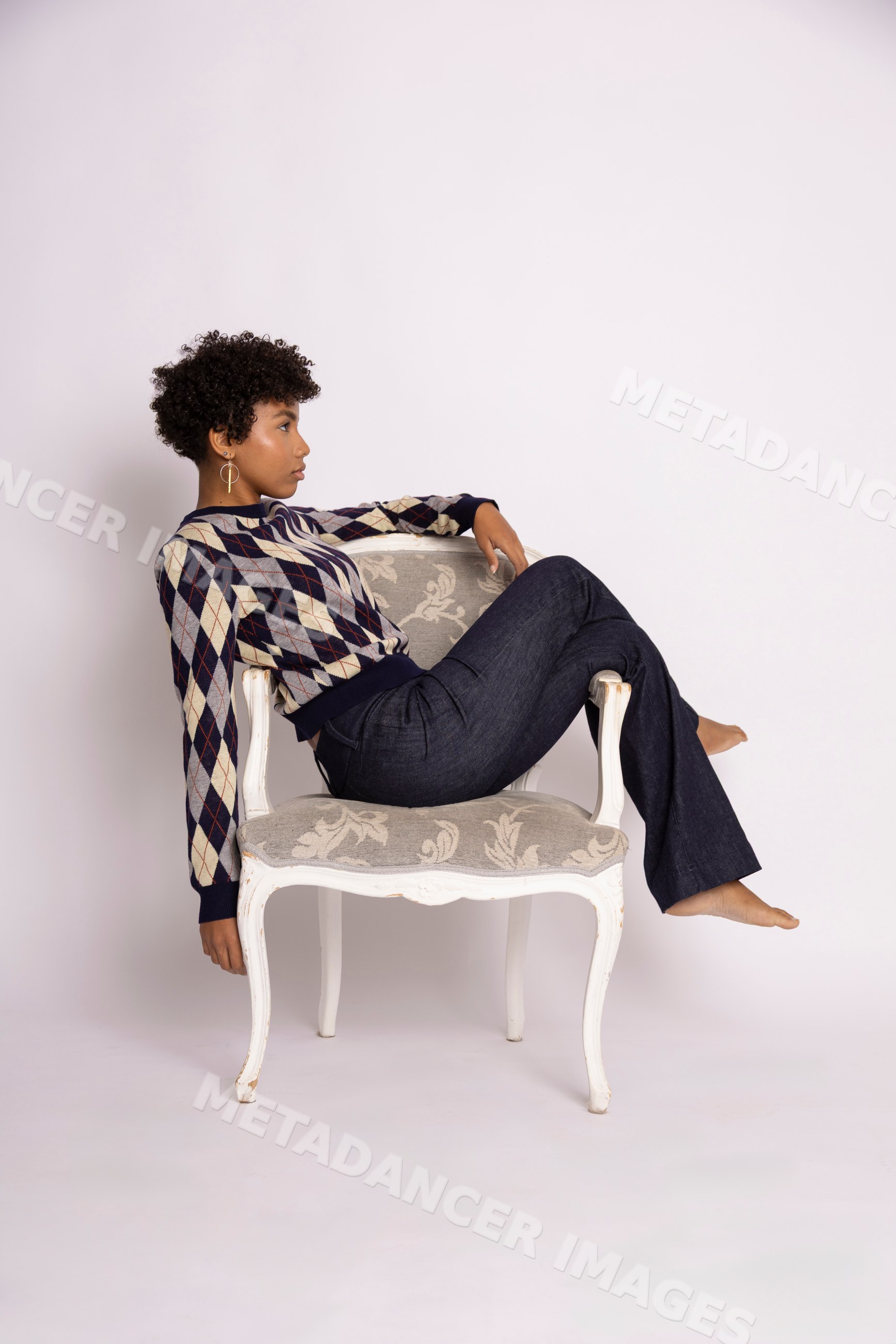 Hispanic woman in argyle sweater and jeans sitting on chair