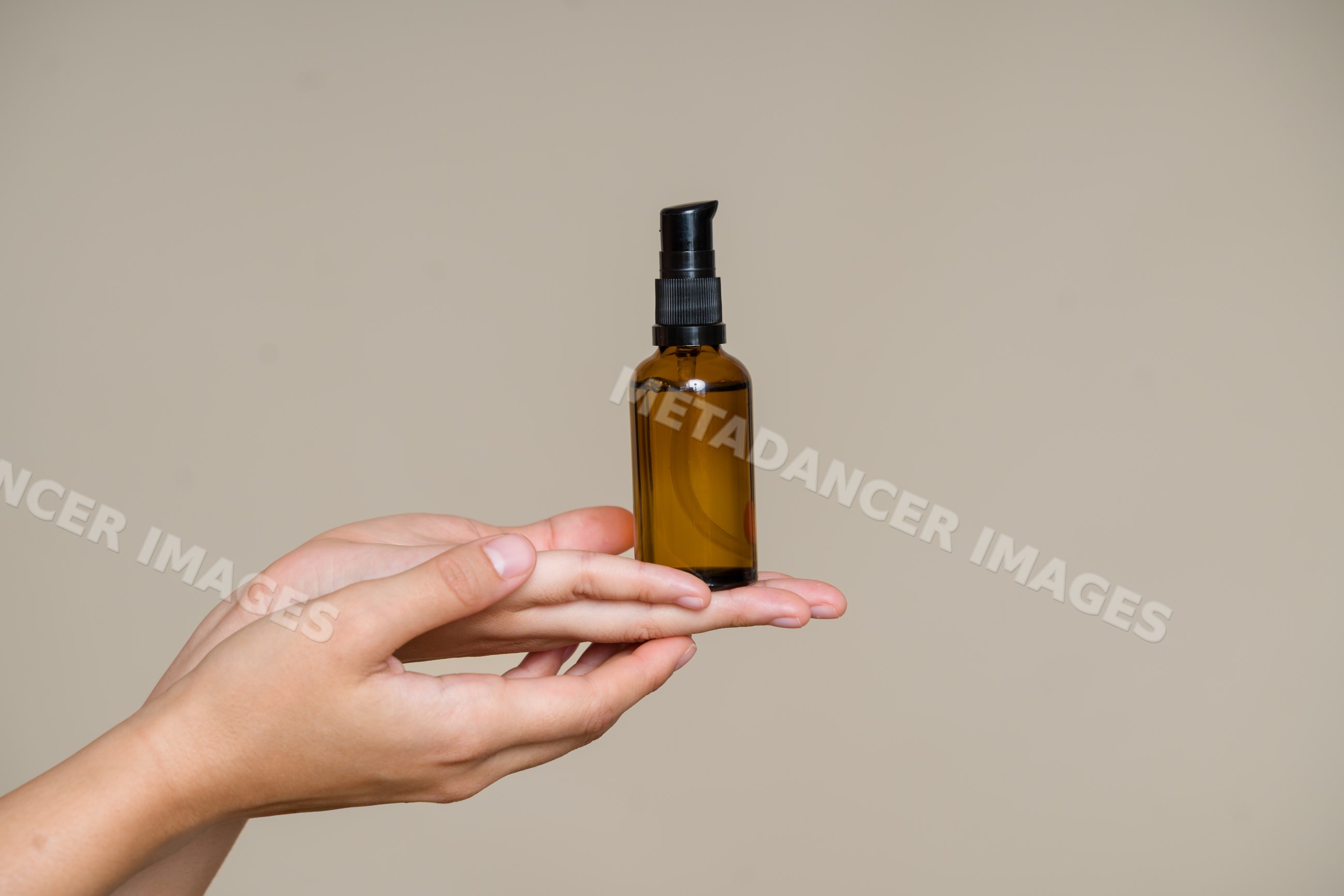 Amber glass bottle with pump dispenser held by hand