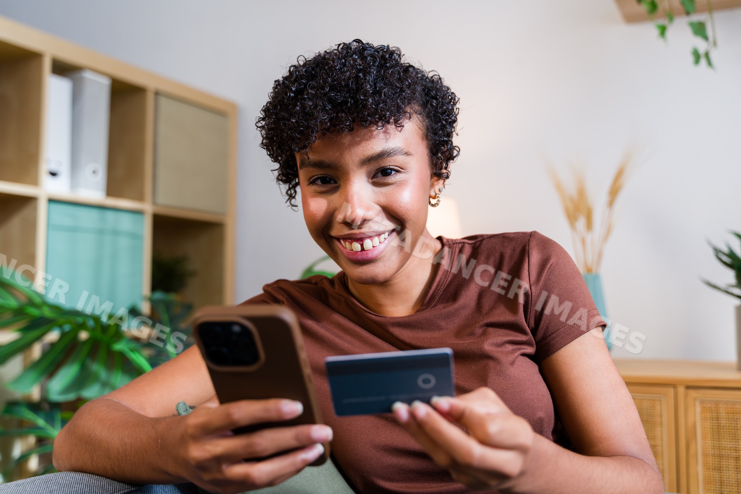 Smiling African American woman using smartphone and credit card
