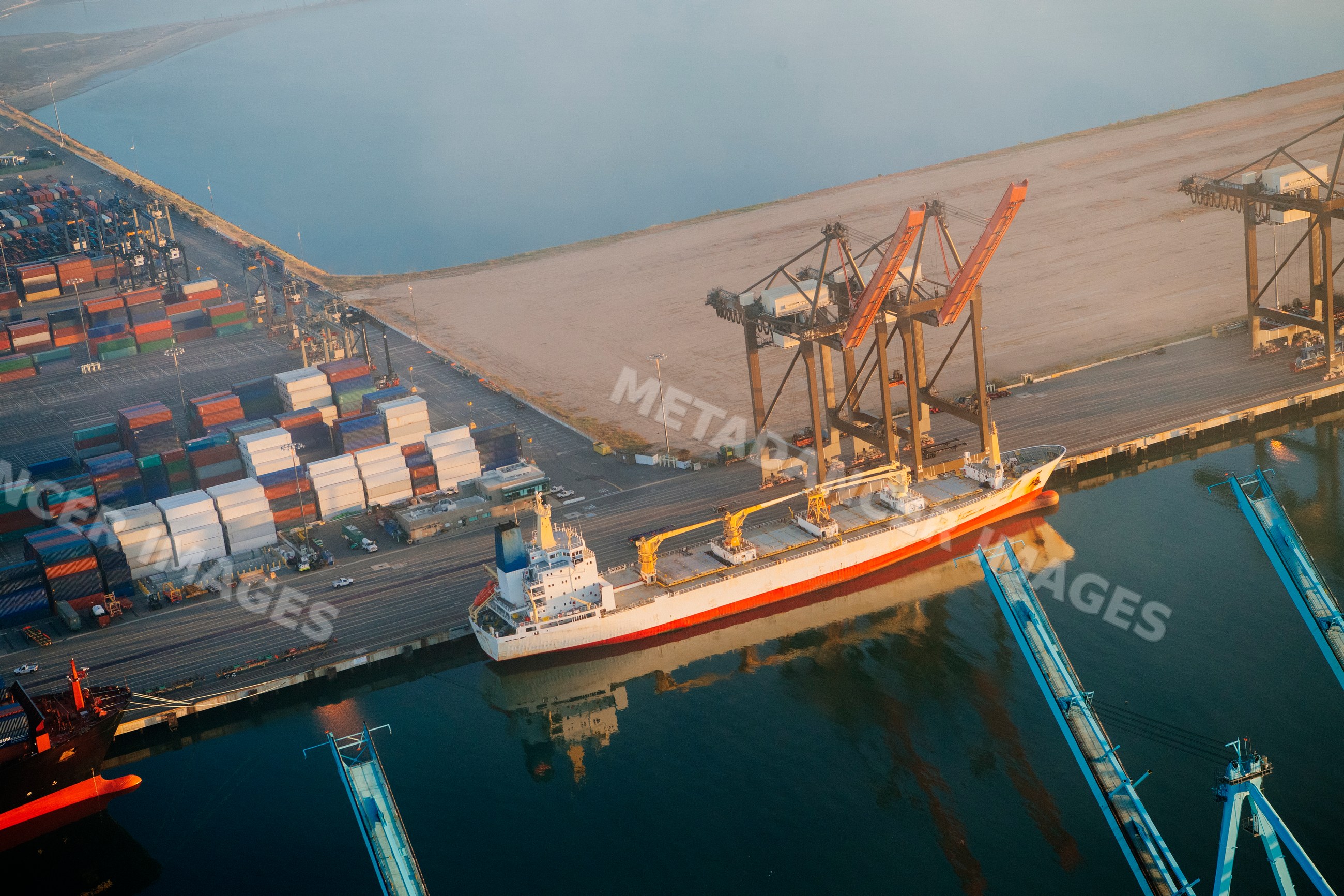 Cargo ship moored at container terminal with cranes at port in long