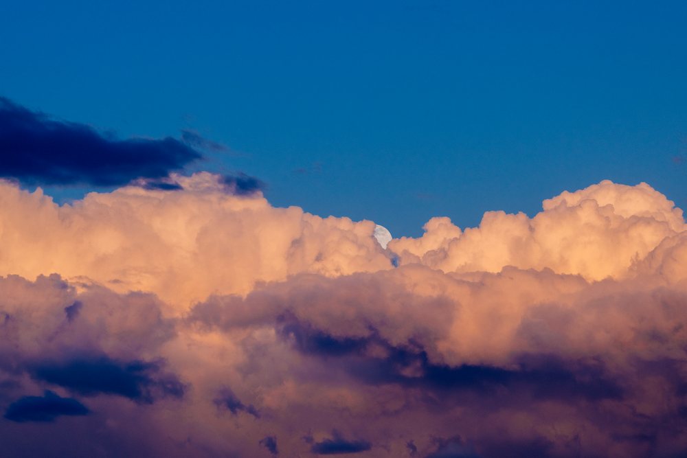 Clouds at sunset with moon partially visible