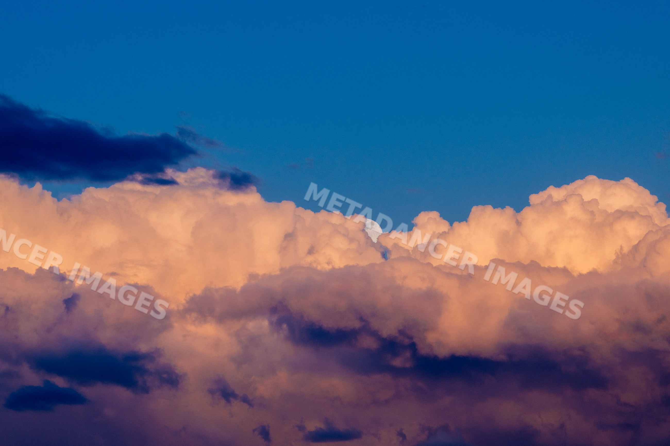 Clouds at sunset with moon partially visible