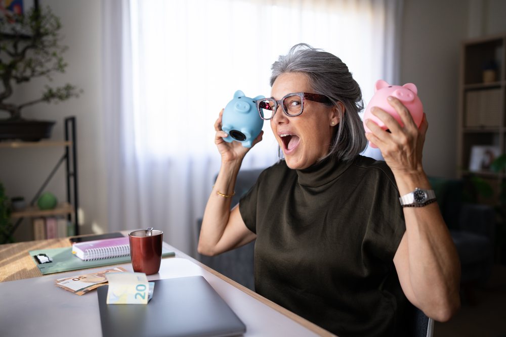 Senior white woman holding piggy banks with euro money