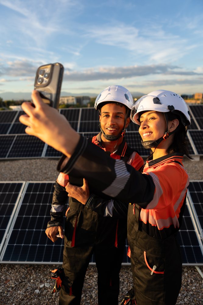 Hispanic workers taking selfie on rooftop solar panel installation