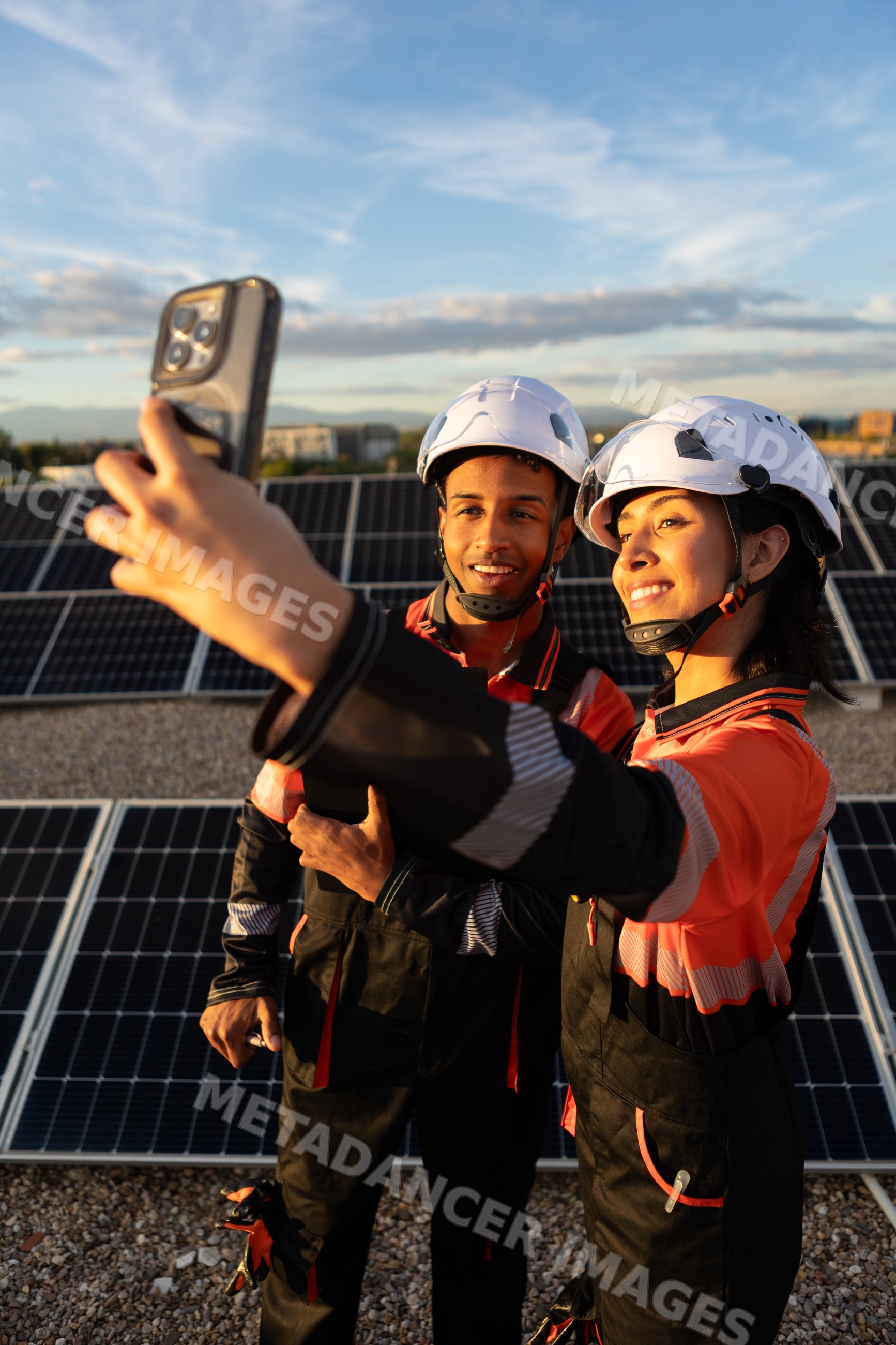Hispanic workers taking selfie on rooftop solar panel installation