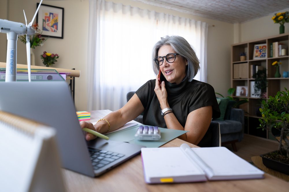 White woman working on laptop and talking on phone