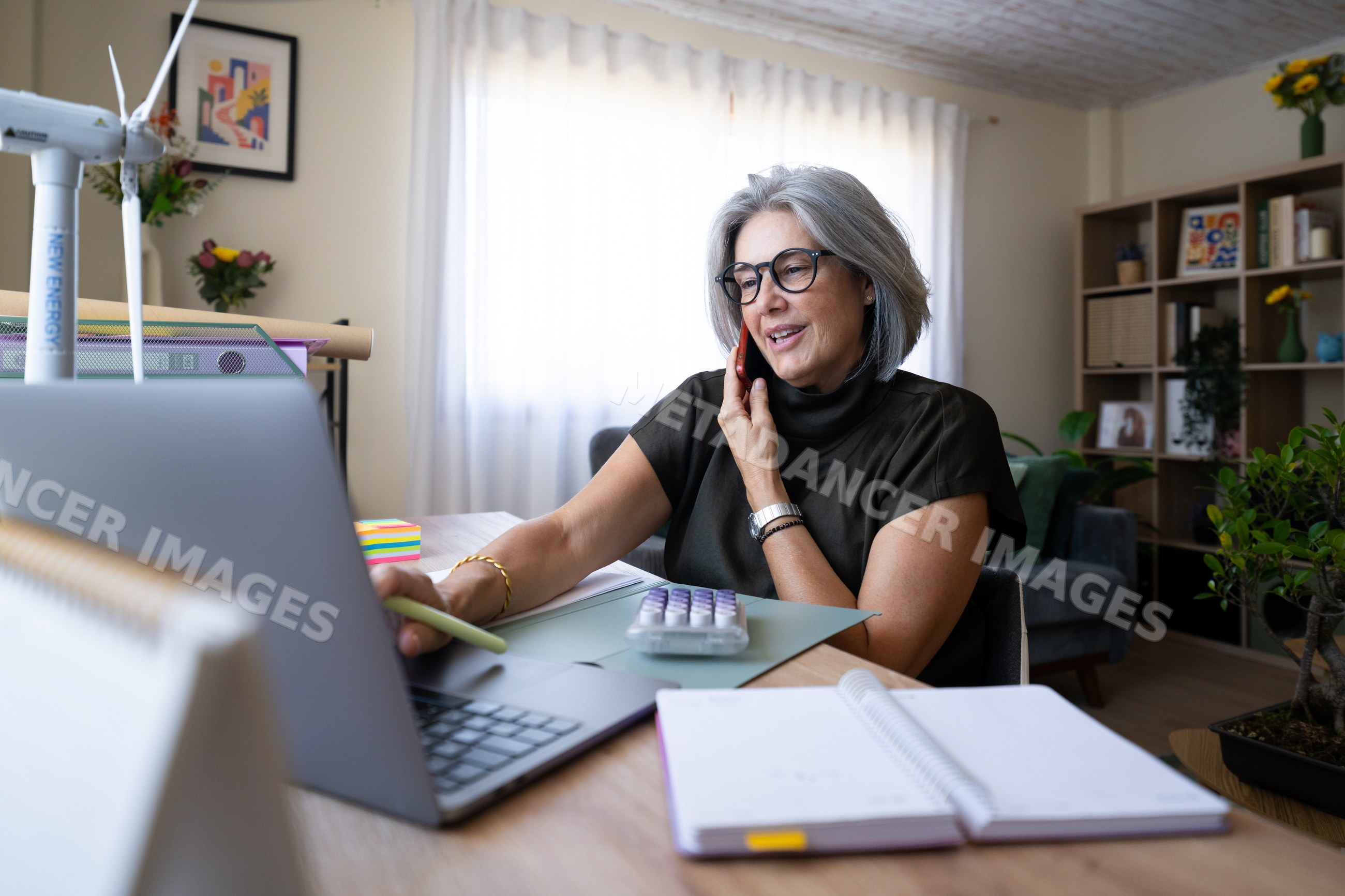 White woman working on laptop and talking on phone