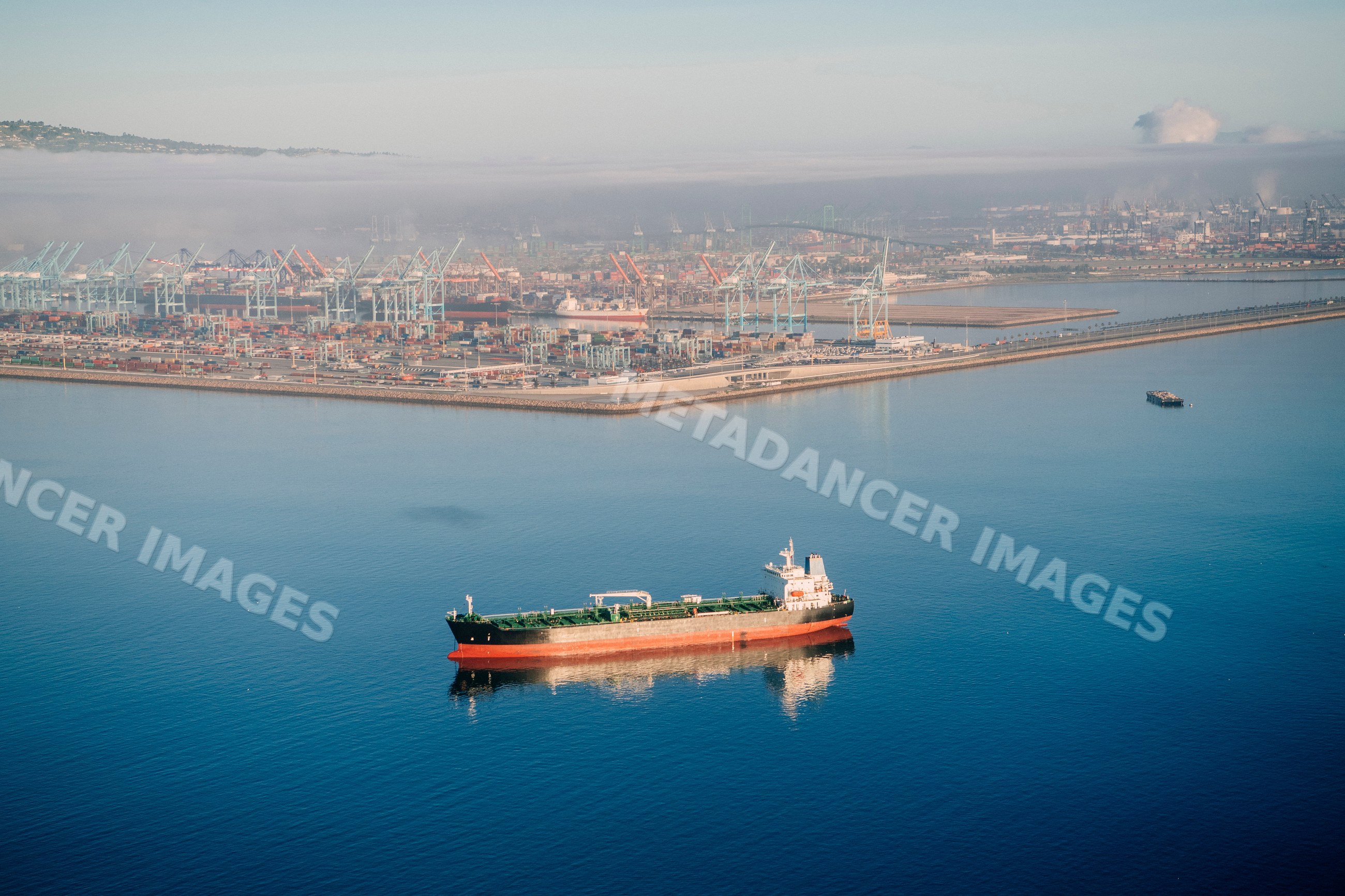 Cargo ship anchored near container cranes at a port in long beach