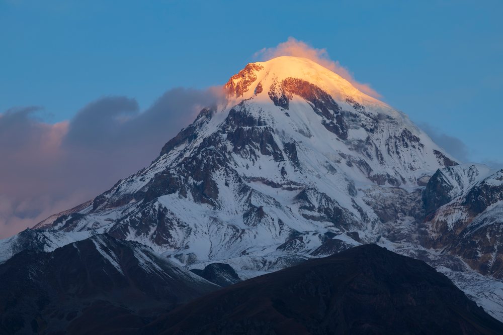 Mt kazbegi Sunrise with glowing snow-capped peak near stepantsminda
