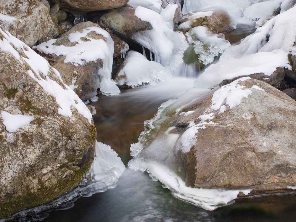 Stream flowing through snow-covered rocks in japan
