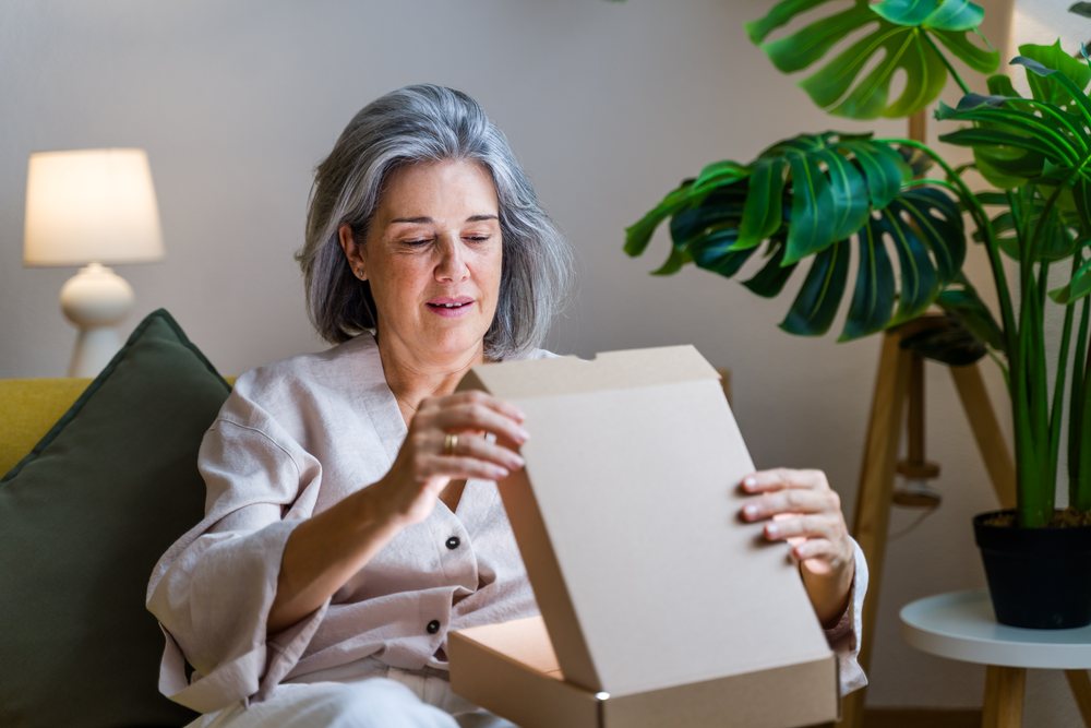 White woman opening cardboard box in cozy living room