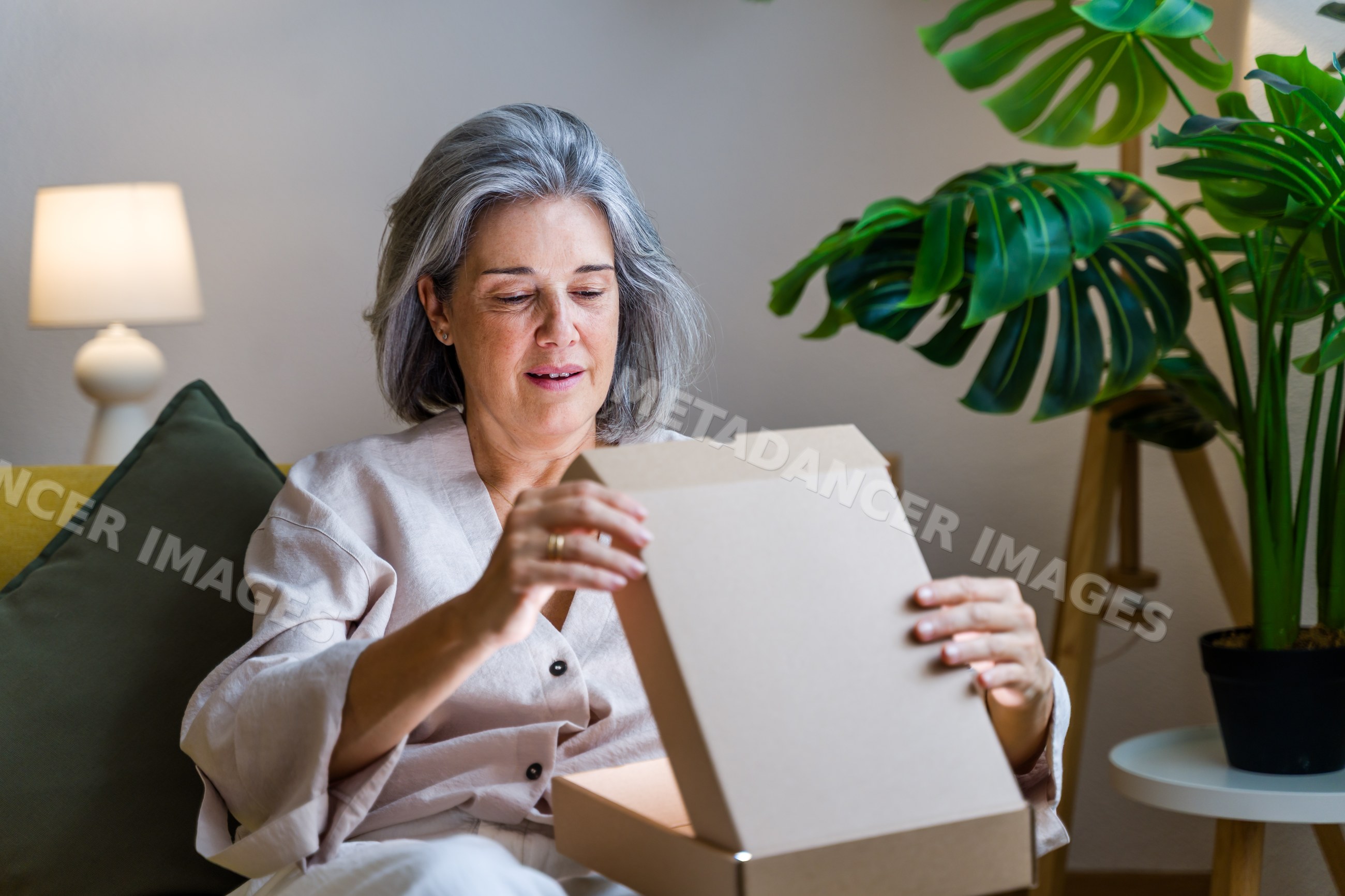White woman opening cardboard box in cozy living room