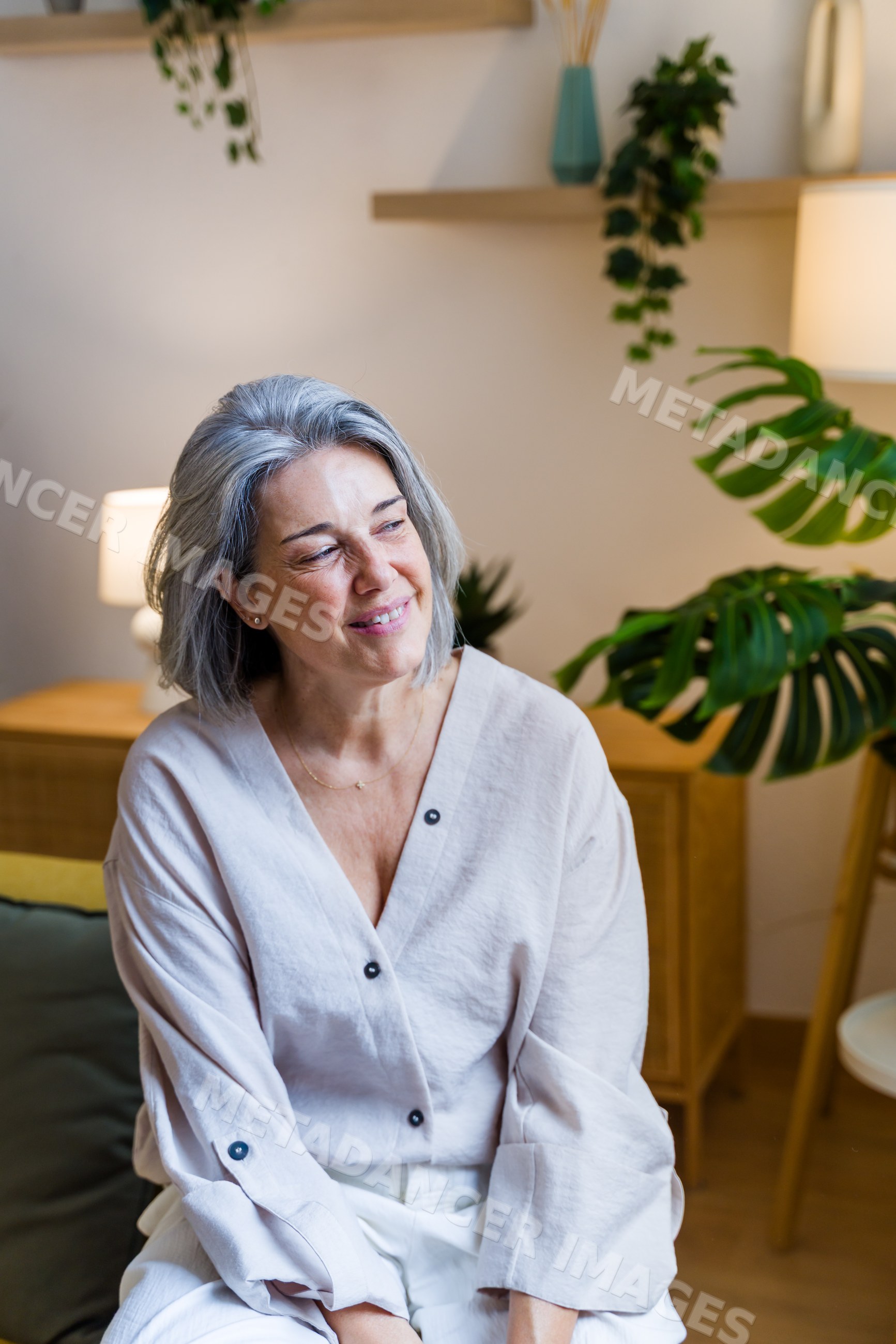White woman with gray hair sitting smiling in modern living room