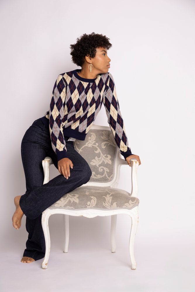 Hispanic woman wearing argyle sweater leaning backward on chair