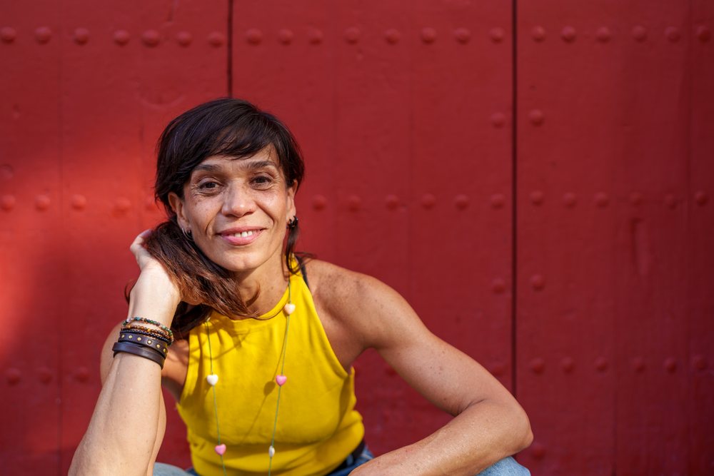 Hispanic woman smiling while sitting against a red metal door