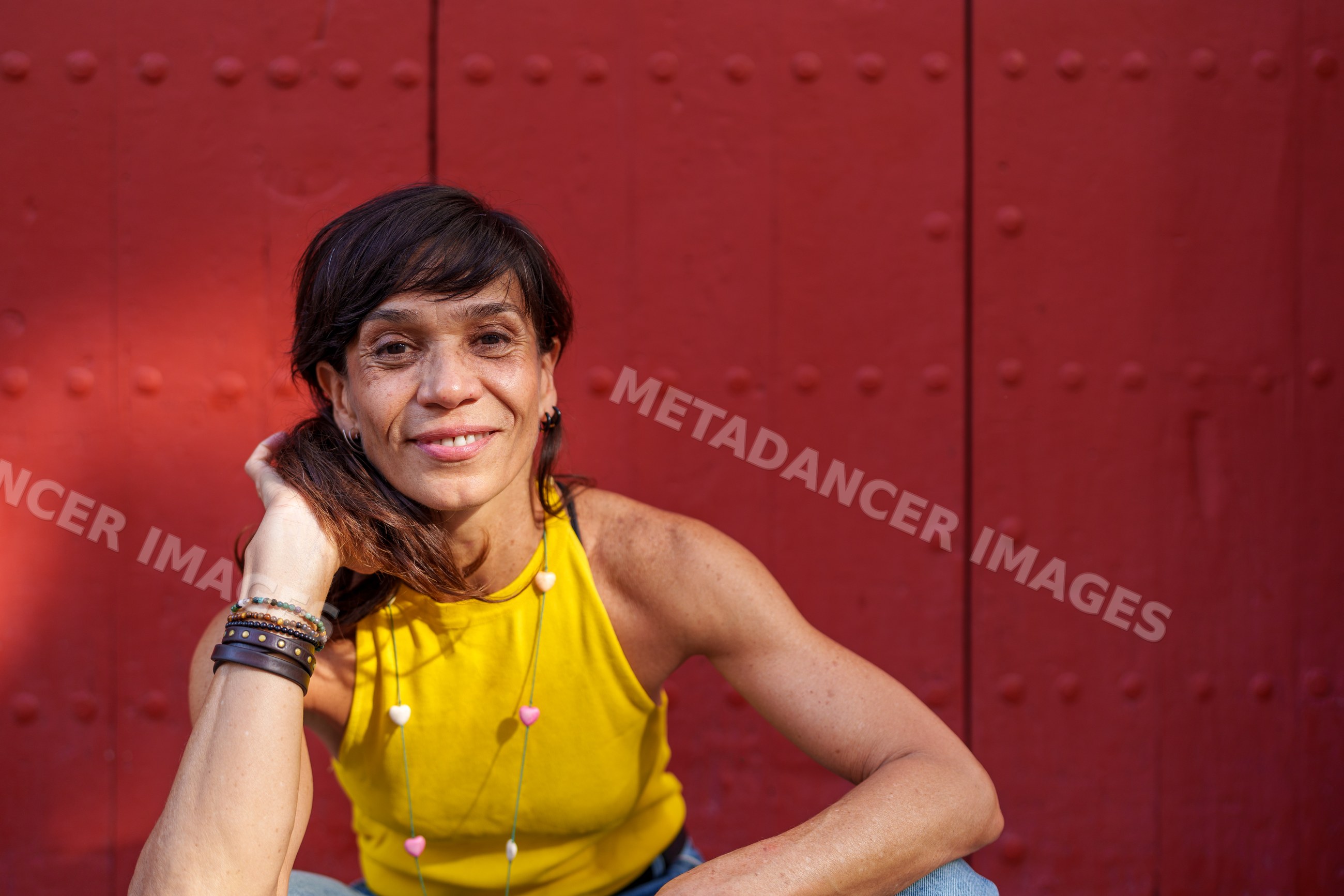 Hispanic woman smiling while sitting against a red metal door