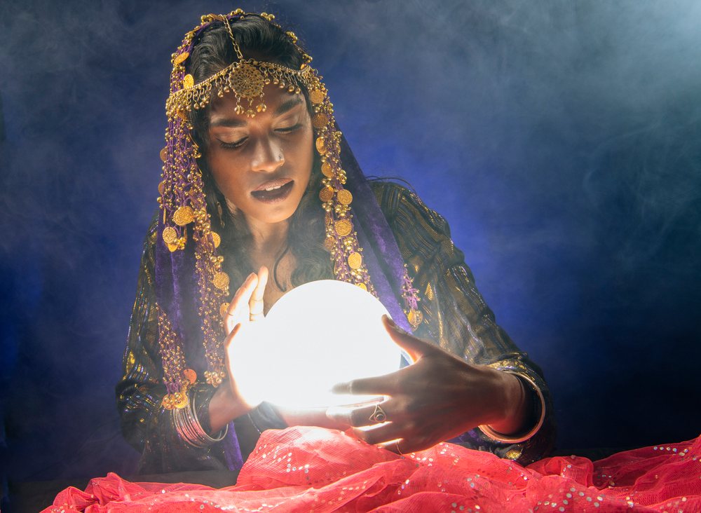 A fortune teller gazes into a glowing crystal ball