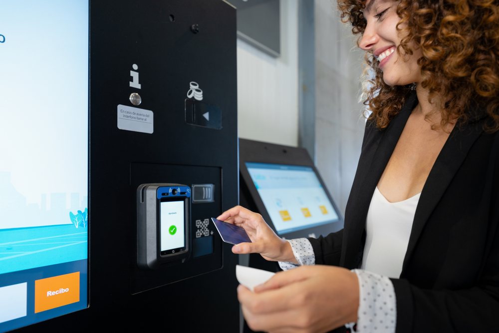 White woman making payment at digital self-service kiosk indoors