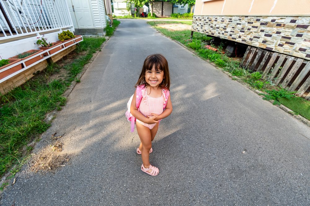 Smiling white girl standing on an asphalt road in a residential area
