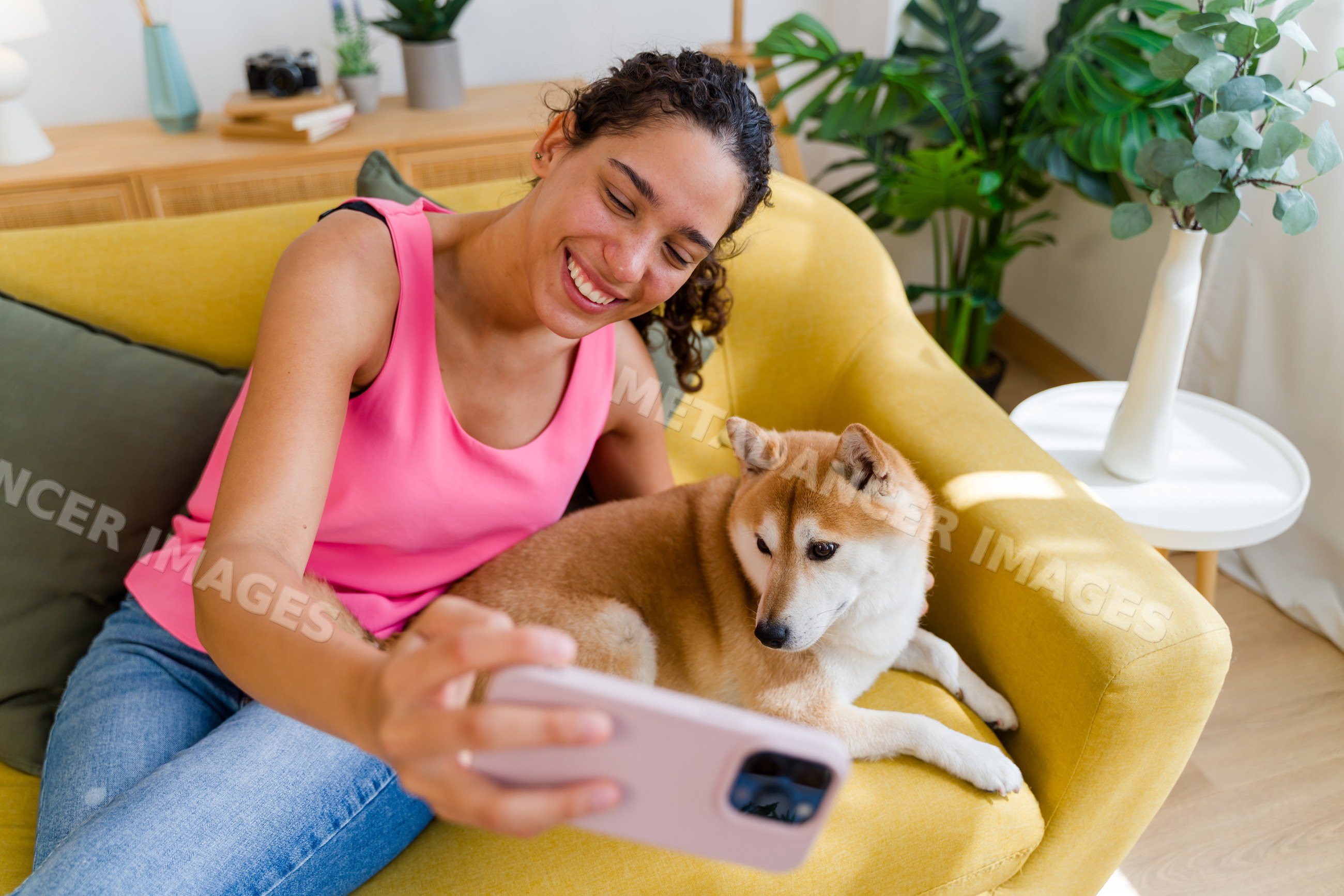 Hispanic Woman taking a selfie with her medium-sized dog on a yellow