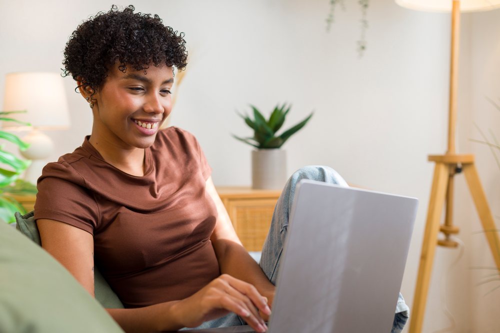 Young African American woman using laptop in cozy home living room
