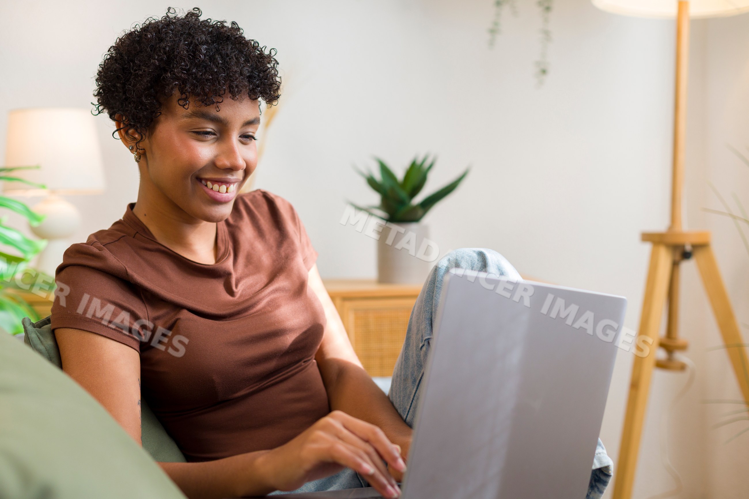 Young African American woman using laptop in cozy home living room