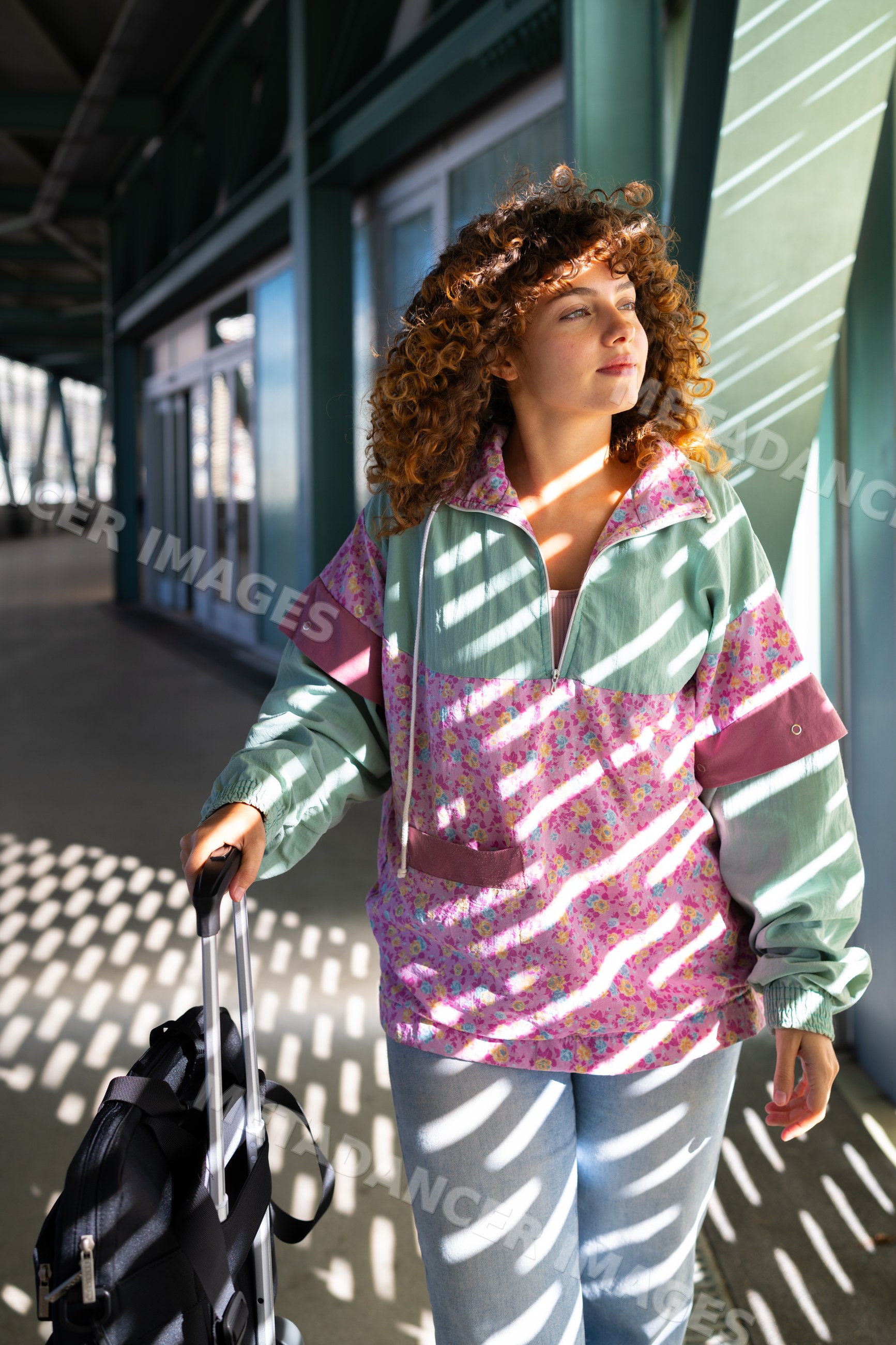 White woman with suitcase standing in sunlit corridor in Spain