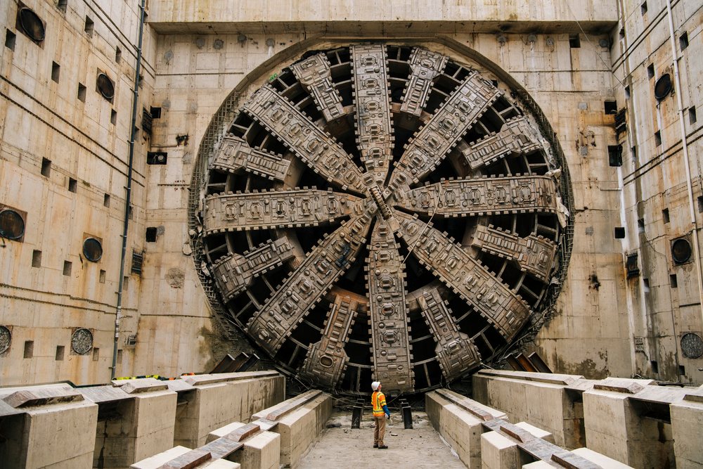 White worker inspects a large tunnel boring machine