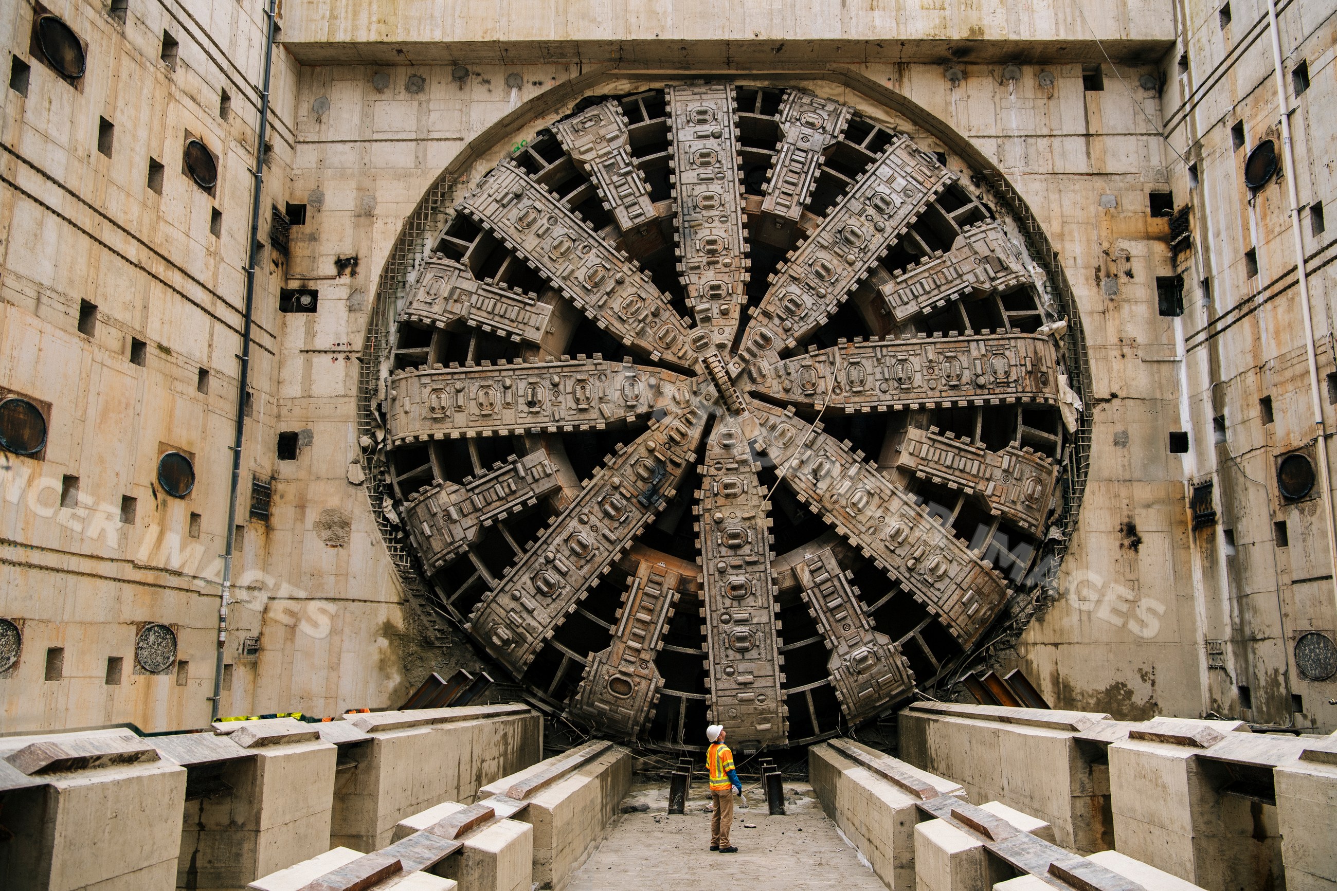 A white worker inspects a large tunnel boring machine